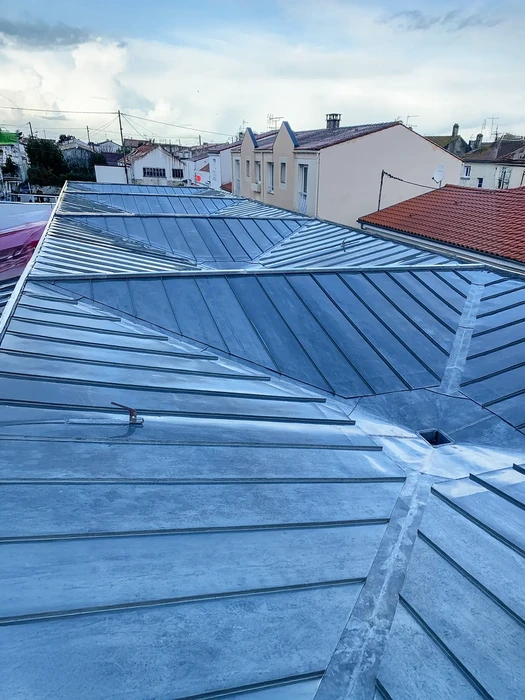 Vue extérieure sur toiture urbaine avec couverture métallique zinc ou plomb, solins et faîtages apparents