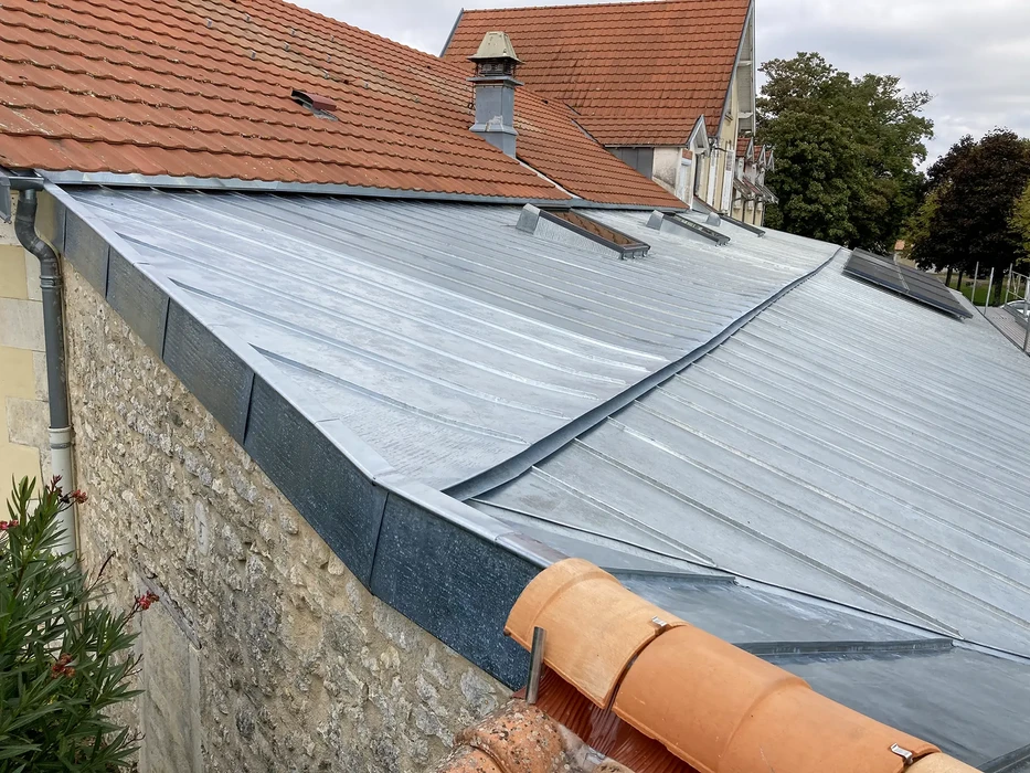 Chantier de couverture en zinc sur toiture urbaine avec pose de bac acier nervuré