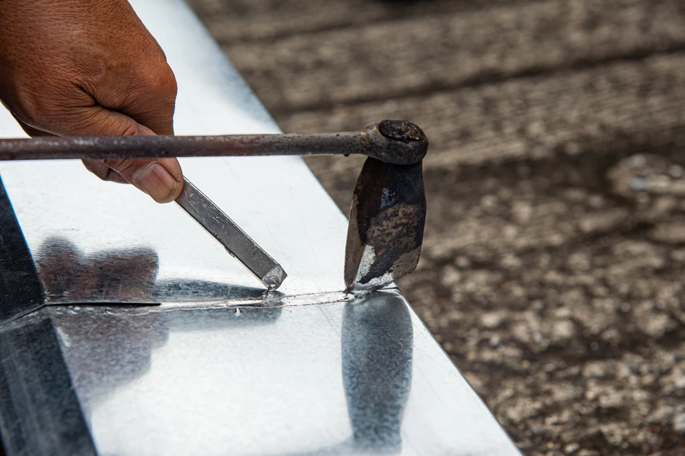 Extérieur d'une maison avec toiture en tuiles ondulées beiges et mur en briques rouges