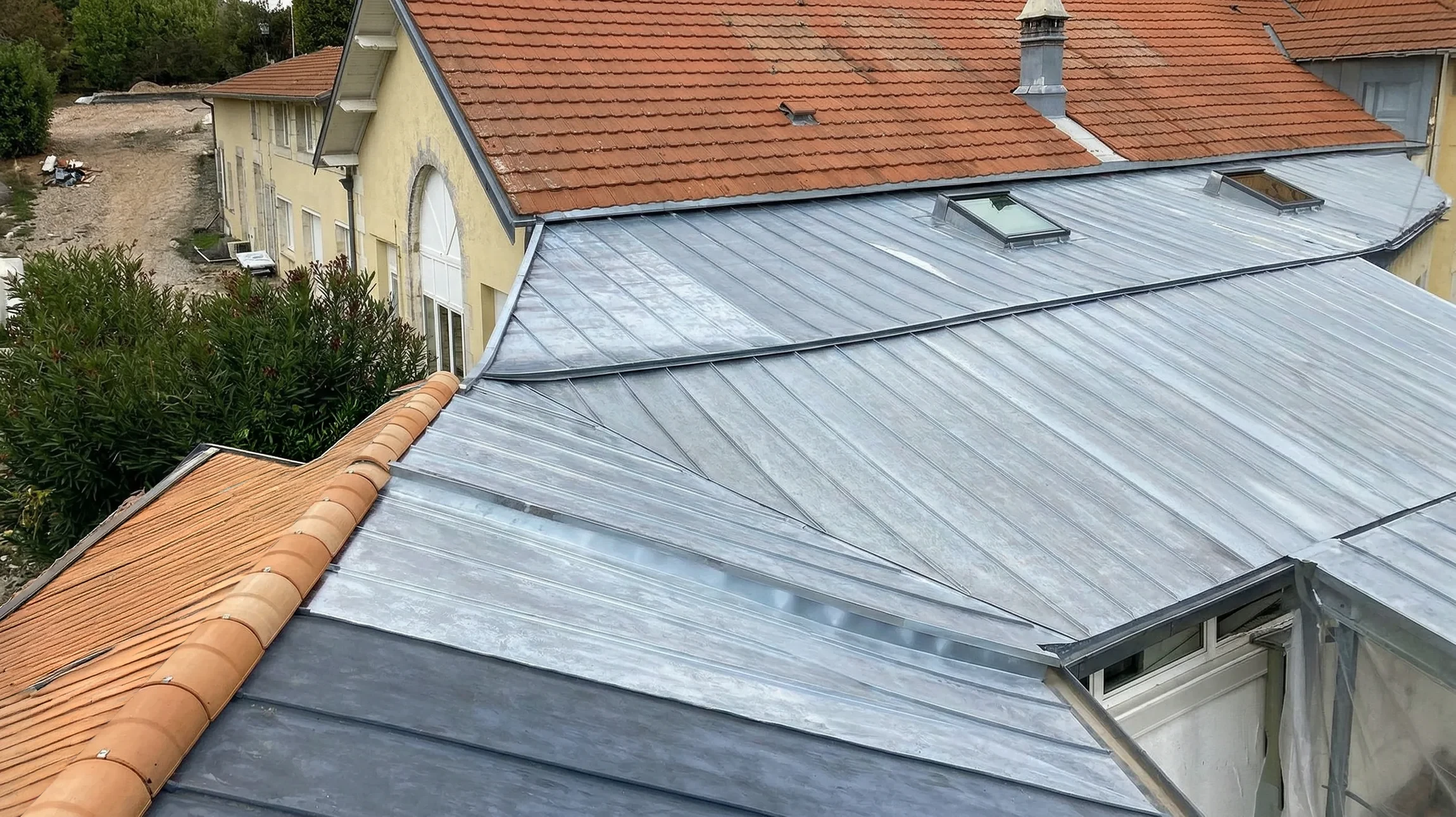 Ouvrier couvreur en silhouette travaillant sur une toiture en pente contre un ciel bleu nuageux