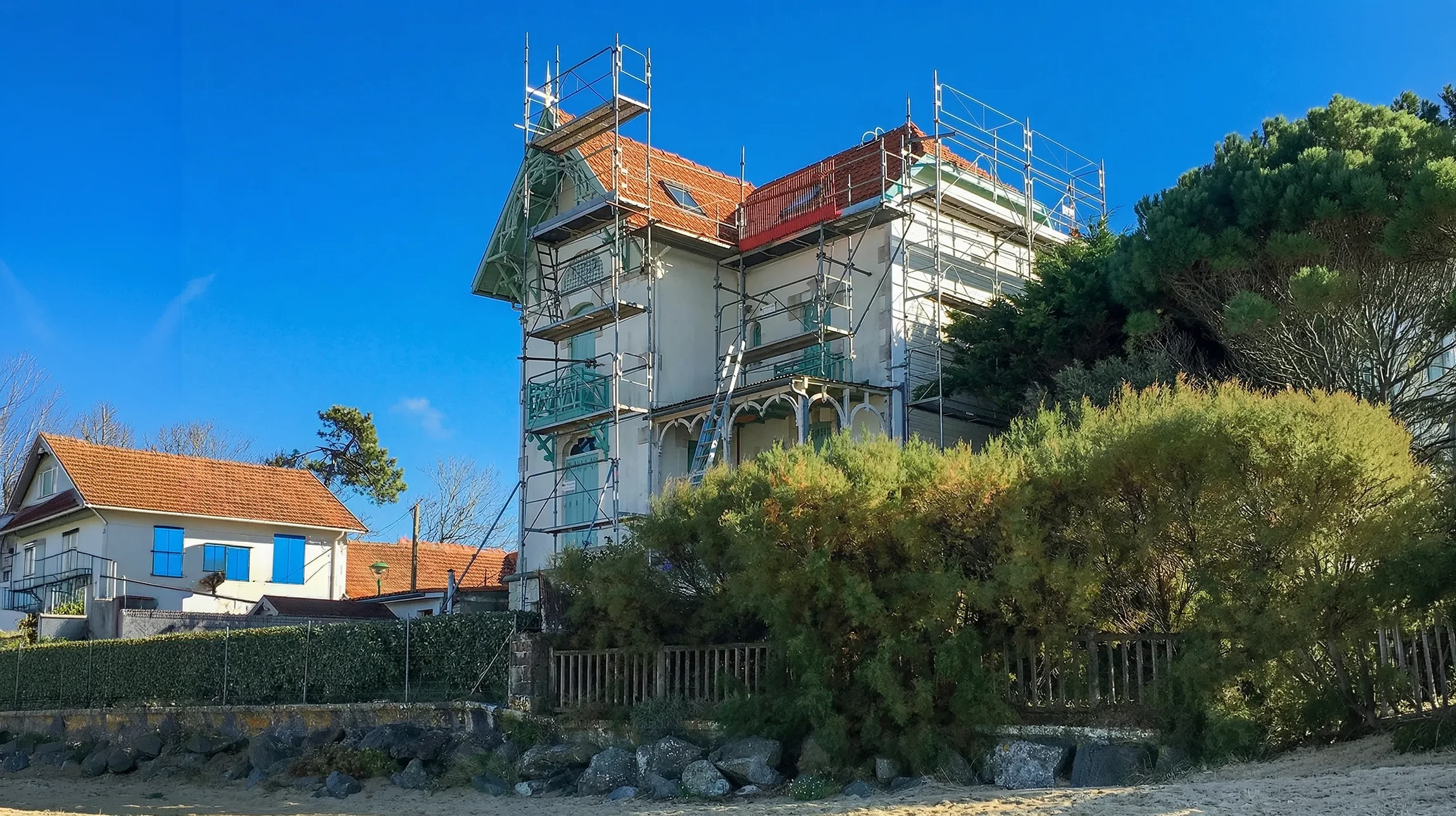 Int&eacute;rieur d'un b&acirc;timent en construction montrant la charpente en bois brut avec poutres principales et secondaires